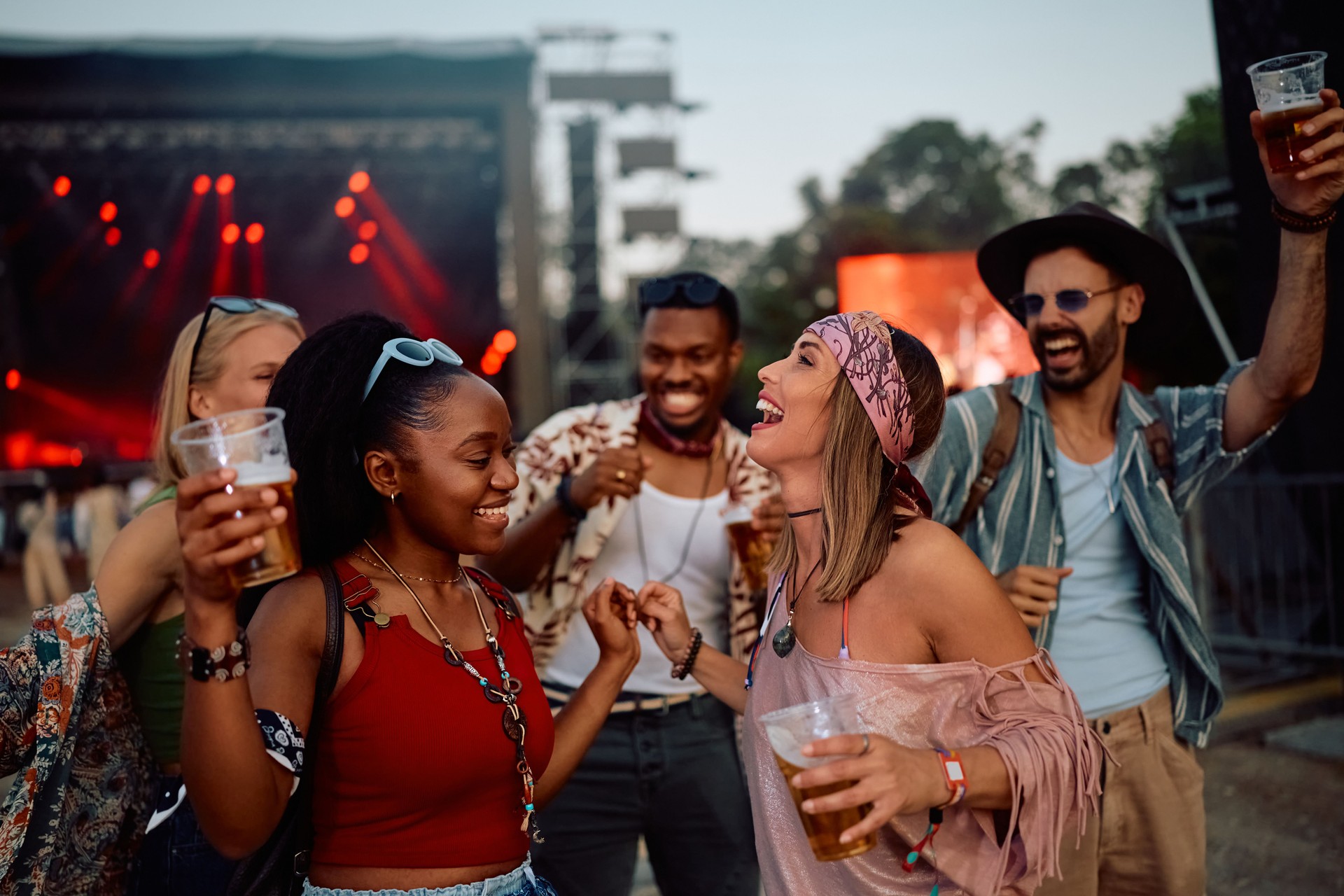 Multiracial group of cheerful festival goers dancing in front of music stage.