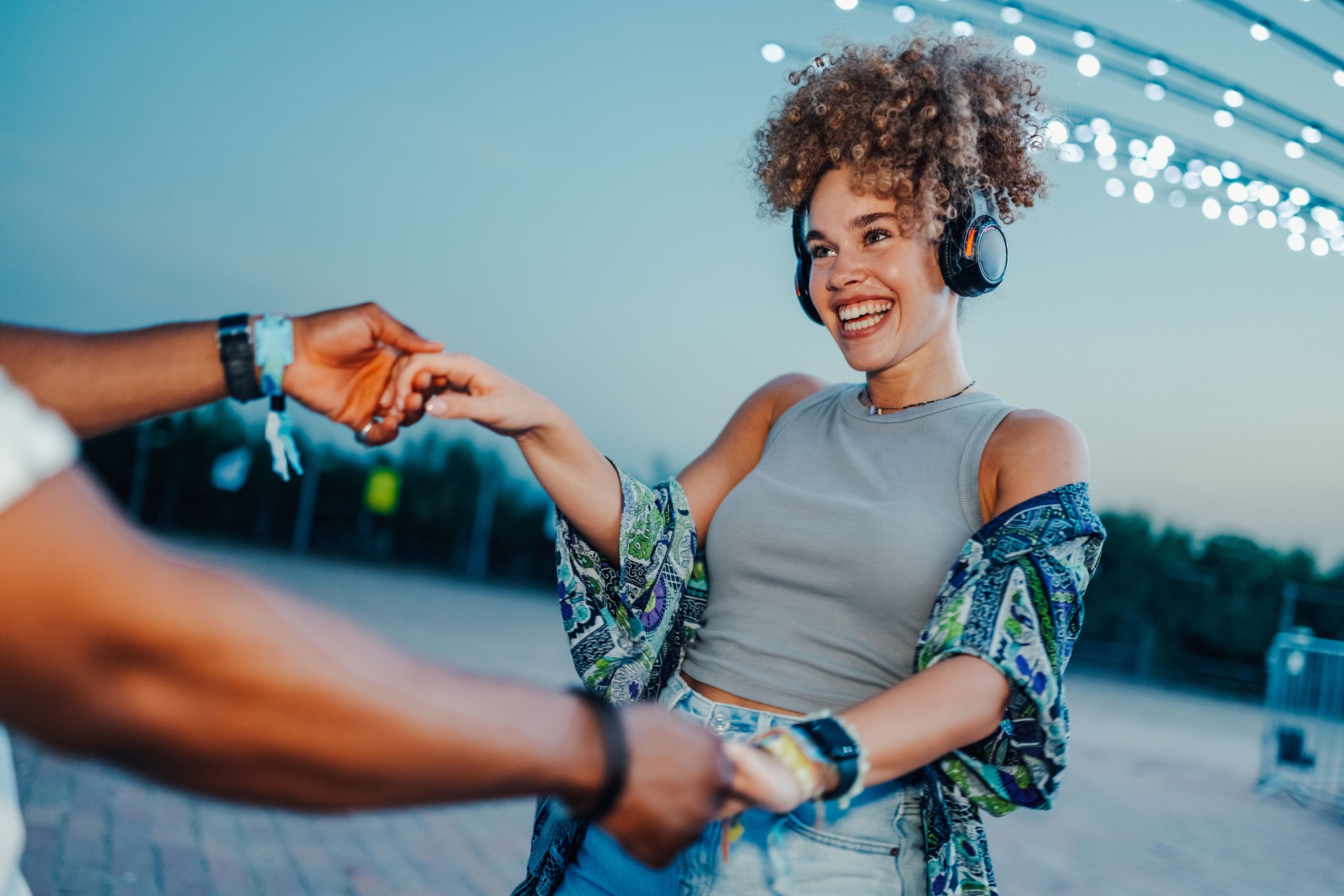 Young woman wearing headphones dancing with a man at a music festival